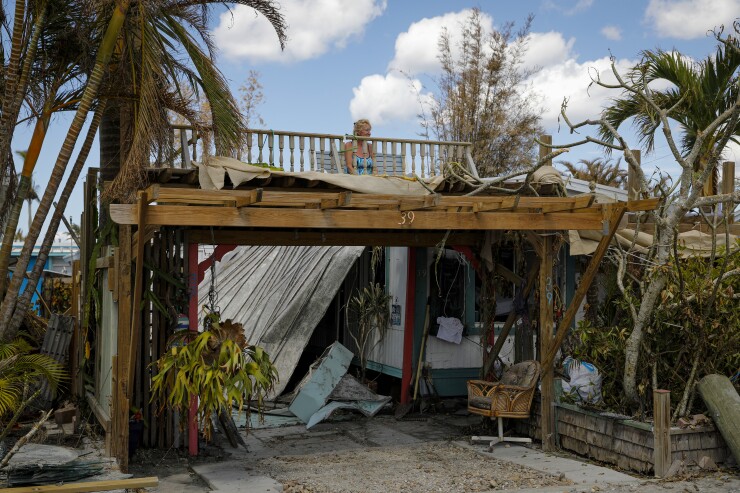 A resident sits on the rooftop of her damaged house in Matlacha, Florida, after Hurricane Ian in 2022.